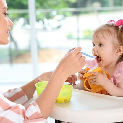  main  fait  manger  bebe  souriant  avec  cuillere  bebe  bleu.