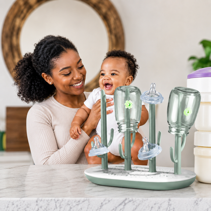 mere bebe joyeux regarde egoutoire biberon sur table.